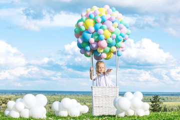 Little cute child girl beautiful and happy on green grass with balloon airship on blue sky background with clouds