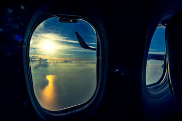 Naklejka premium The window of the airplane flying in sunset