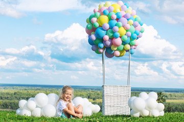 Little cute child girl beautiful and happy on green grass with balloon airship on blue sky background with clouds