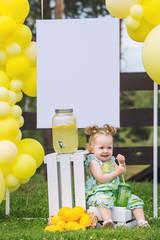 Little cute baby girl beautiful and happy on green grass with balloons and lemonade