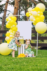 Little cute kids, two girls, beautiful and happy on the green grass with balloons and lemonade