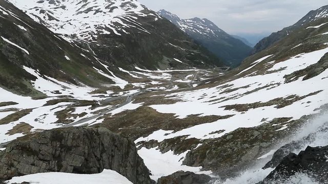 Beautiful waterfal near the Susch pass near Davos in Swizerland surrounded by snow. Filmed in slowmotion in June.