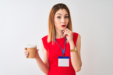Redhead businesswoman wearing id card drinking cup of coffee over isolated white background serious...
