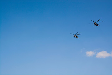 Two gray military helicopters fly in the blue sky. Demonstration of a peaceful flight. Day of the city. Memory. Air show Background with copy space for text.