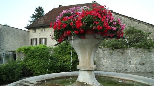 Fountain with vase and flowers in the small town in France. Filmed in slow motion.