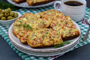 Homemade hot sandwiches with cheese and sausage in a plate on a checkered tablecloth, horizontal orientation