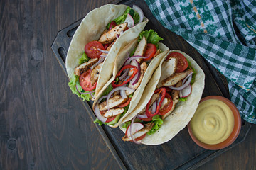 Mexican dish.Taco with chicken and vegetables close-up on a wooden background. Space for text.