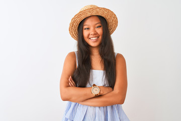 Young chinese woman wearing striped dress and hat standing over isolated white background happy face smiling with crossed arms looking at the camera. Positive person.