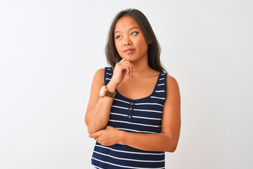 Young chinese woman wearing striped t-shirt standing over isolated white background with hand on chin thinking about question, pensive expression. Smiling with thoughtful face. Doubt concept.