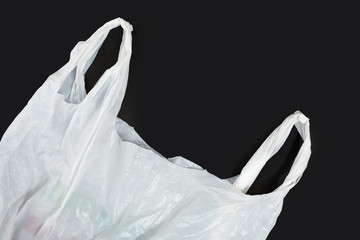 white plastic bag on black background. A White Plastic Bag Texture, macro, background. Reduction of plastic bags for natural treatment. The symbol of the campaign to refrain from using plastic bags.
