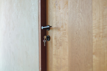 Selective focus on modern style of knob on wooden door with keys hanging on lock