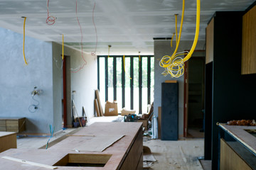 Selective focus on electrical wire hanging from ceiling with perpsective of house under construction