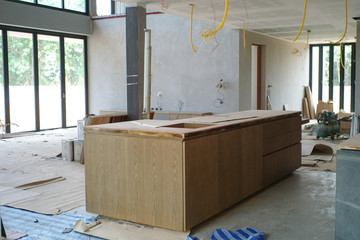 Selective focus on wooden kitchen island under installation in the house under construction