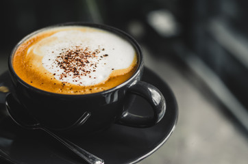 close up modern hot black coffee the cappuccino on dark background with coffee bubble foam pattern and texture in black cup looking and feel so delicious on glasses table in coffee shop.