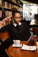 Black african american young yoman drinking coffee and using a tablet