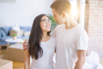 Young beautiful couple standing at new home around cardboard boxes