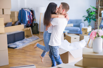 Young beautiful couple hugging at new home around cardboard boxes