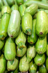 a lot of green fresh squash, the counter of the village vegetable market, new harvest, useful vitamins. vertical photo, vegetables are beautifully arranged in rows.