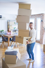 Fototapeta na wymiar Young couple moving to a new house, man holding cardboard boxes worried about falling for overweight
