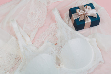 White women underwear with lace and gift box on beige background. white bra and pantie.Copy space. Beauty, fashion blogger concept. Romantic lingerie for Valentine's day temptation. Erotic concept.