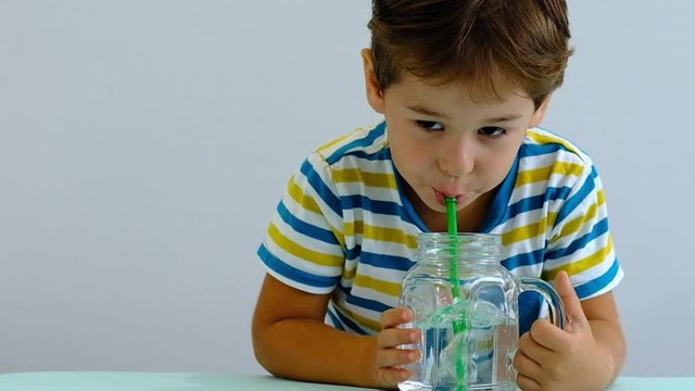 slow motion asian Cute little kid drinking water on kitchen. cheerful boy likes to blow bubbles