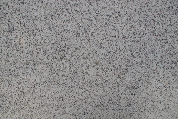 Gray asphalt sidewalk with inclusions of small pebbles during the beginning of the rain with spots of moisture, the background of urban coverage