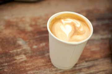 Beautiful cappuccino with a heart in a paper cup