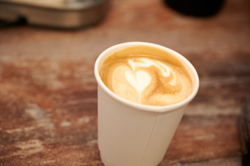 Beautiful cappuccino with a heart in a paper cup