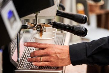 Fototapeta na wymiar Barista making espresso drinks to paper cups