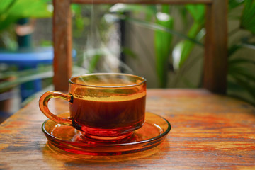 Hot coffee cup on glass cup with smoke on wooden chair table background. Top view