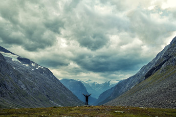 Happy man gesture of triumph with hands in the air. Funny hiker on the peak of sandstone rock in...