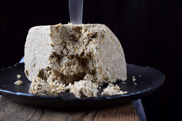 Big piece of sunflower and sesame halva on wooden table against black background. Eastern dessert