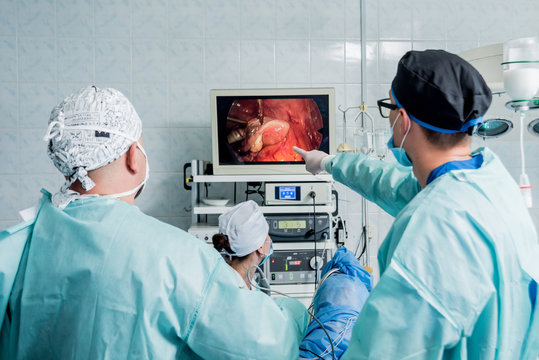 Process of gynecological surgery operation using laparoscopic equipment. Group of surgeons in operating room with surgery equipment.