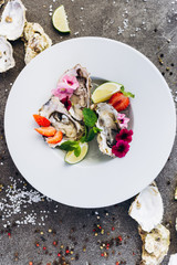 Oysters on a dish decorated with flowers on a gray background. Aphrodisiacs. 