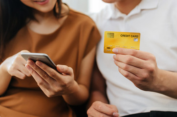 young couple man and woman entering security code on mobile smart phone and paying credit card on...
