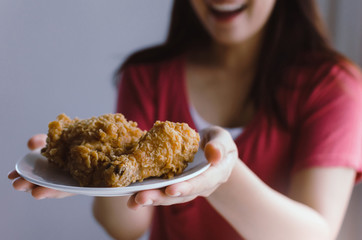 asian young pretty woman slim body smiling and holding delicious crispy fried chicken on dish in kitchen at home office, junk food, unhealthy food, dieting, weight loss and good healthy concept