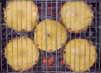 Slices of fresh pineapple sprinkled with sugar are fried on the grill 