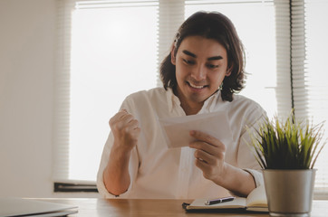 happy young asian employee business man holding money bonus card in paper envelope to increasing of salary or promotion new position in office, new job celebrate salary and resignation letter concept