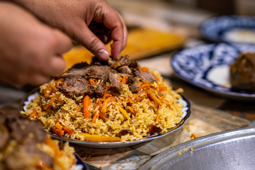 Serving traditional Uzbek pilaf from rice, meat, carrots