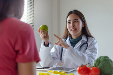 Nutritional. friendly nutritionist female doctor medical talking about diet plan with green apple and vegetable to young patient woman in office hospital, nutrition, food science, healthy food concept