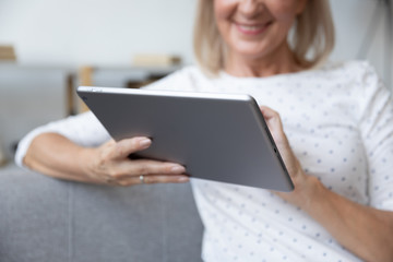 Smiling mature woman using computer tablet close up