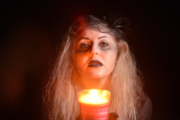 Beautiful young woman with a candle in her hands. Halloween witch concept.