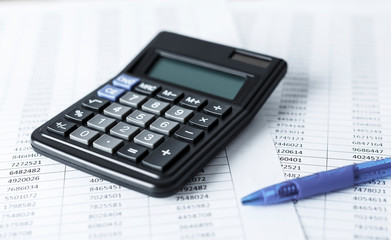 Calculator with pen on white paper with numbers. Business and Finance accounting concept.