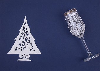 Naklejka na ściany i meble Christmas greeting card with decoration Christmas tree made of sugar icing and wine glass decorated with icing on deep blue background. Top view. Copy space.