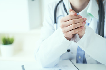 Young woman doctor listens attentively to patient complaints, hands clasped one on top of the other. Doctors and patients sit and talk to the patient about medication.