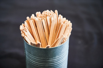 Wooden stirrers in a tin can isolated on black background