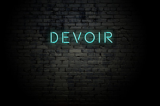 Highlighted brick wall with neon inscription devoir