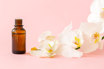 Massage oil. Orchid flower with natural oil in the Spa salon. Spa concept with white orchids on a pink background.  