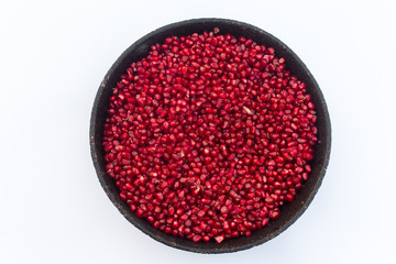 red pomegranate seeds in a bowl on white background
