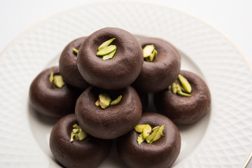 Chocolate Milk peda or pera or pedha made using sweet condensed Milk and cocoa powder, garnished with Pistachio. selective focus